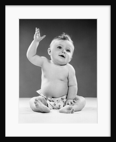 1950s portrait of baby sitting one arm raised waving by Anonymous