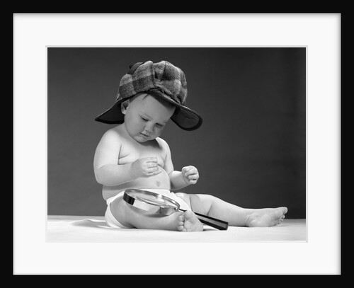 1960s baby in diaper wearing sherlock holmes deerstalker style double-billed cap with magnifying glass resting on leg inspecting a clue by Anonymous