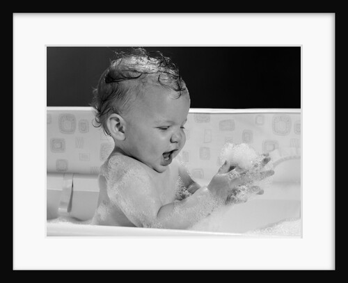 1960s baby in bathtub playing with suds indoor by Anonymous