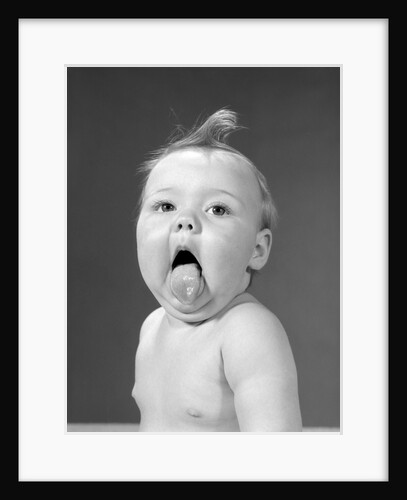 1960s baby with curl on top of head & tongue sticking out by Anonymous