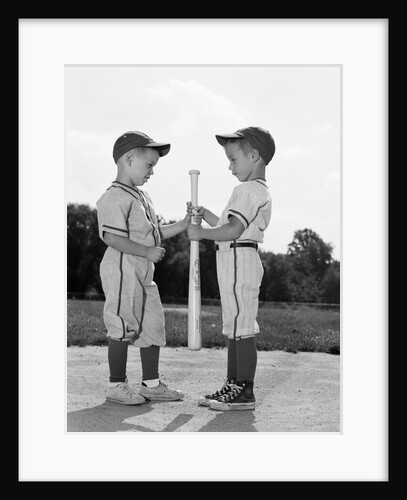 1960s two boys in baseball uniforms choosing sides by getting the upper hand on a bat by Anonymous