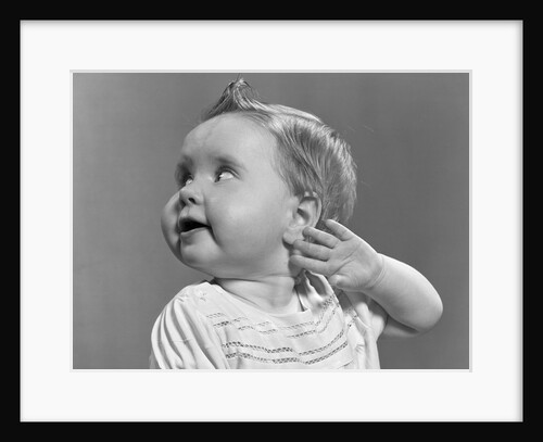 1940s 1950s close-up portrait of baby girl with curl on top of head looking to side with hand held up beside ear by Anonymous