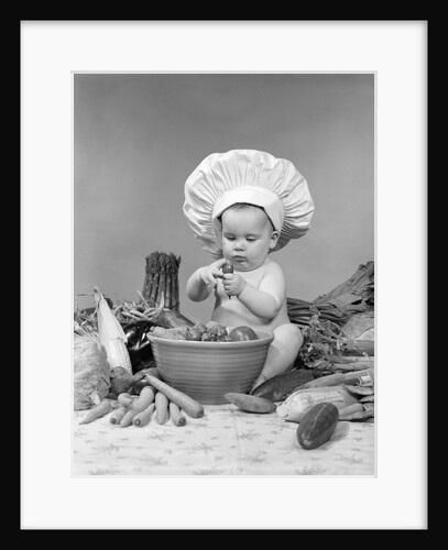 1950s 1960s baby wearing chef hat toque bowl and raw vegetables making a salad by Anonymous