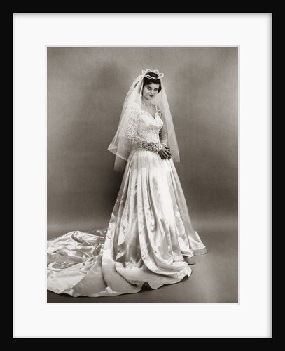 1950s full length portrait bride standing wearing satin and lace wedding gown veil and tiara looking at camera by Anonymous