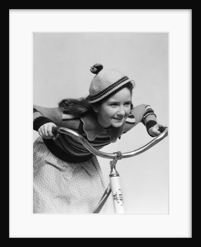 1930s smiling eager little girl in knit cap and matching sweater riding bike leaning into handlebars by Anonymous