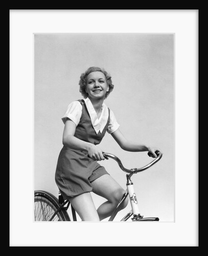 1930s smiling blonde woman riding bicycle looking at camera by Anonymous