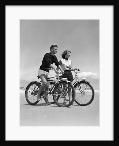 1950s teenage boy and girl with bikes on the beach by Anonymous