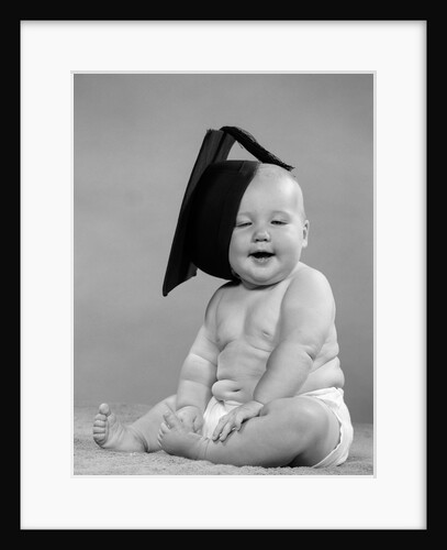 1950s portrait chubby baby in diaper with tilted mortar board on head school graduation higher education studio by Anonymous
