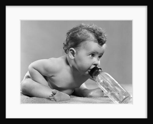 1950s baby sitting leaning forward drinking from bottle studio indoor by Anonymous