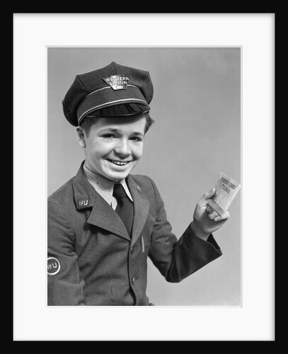 1920s 1930s 1940s smiling boy wearing a western union uniform and hat holding a telegram looking at camera by Anonymous