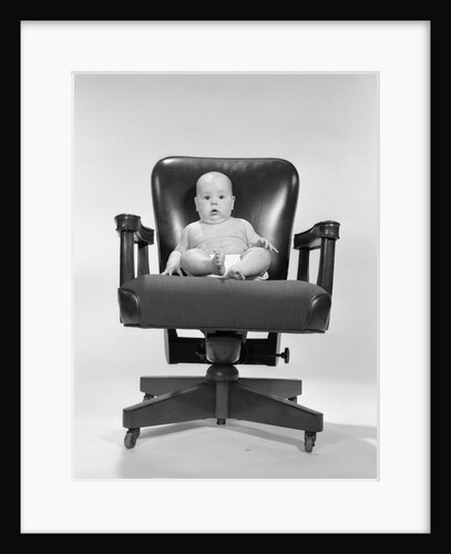 1960s baby sitting in executive office chair looking at camera by Anonymous