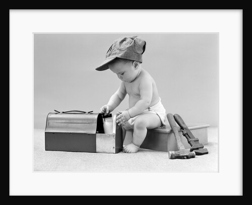 1940s baby in railroad engineer hat pulling milk bottle from lunch pail with hammer & wrench tools at side studio by Anonymous