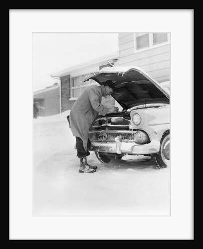 1950s man winter driveway trying to start fix car hood up by Anonymous
