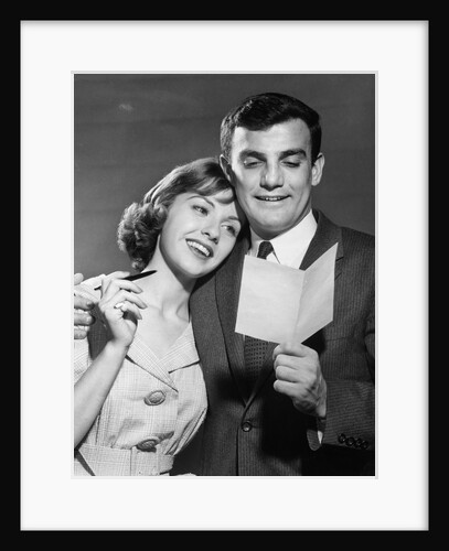 1960s couple reading letter happy woman resting head on mans shoulder by Anonymous