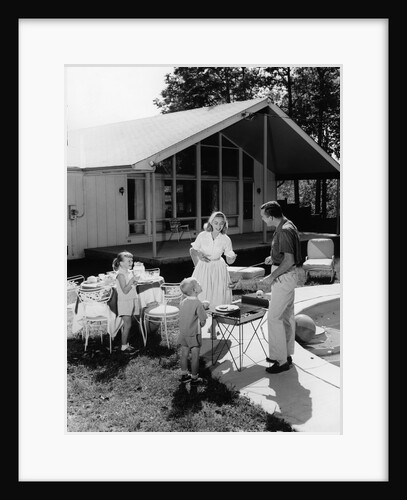 1950s family grilling hamburgers beside pool in backyard cookout by Anonymous