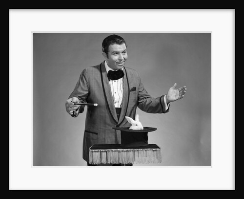 1960s man magician wearing tuxedo white rabbit peaking our of top hat by Anonymous