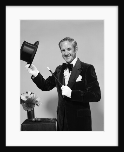 1970s smiling man magician wearing velvet tuxedo white gloves pointing magic wand at top hat looking at camera by Anonymous