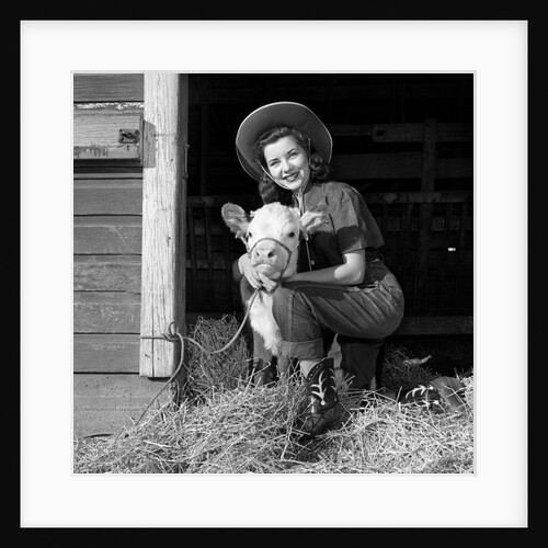 Girl posing with calf in straw filled stall in barn by Anonymous