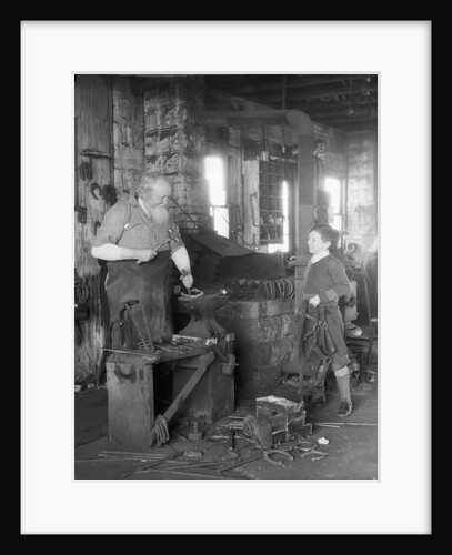 1930s elderly blacksmith with hammer at anvil as young boy holding harness looks on smiling by Anonymous