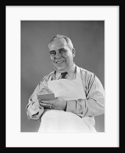 1940s man wearing white apron writing order on pad with pencil looking at camera by Anonymous