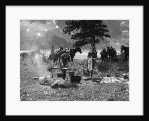 1920s 1930s two women at campsite woman cooking preparing food over campfire horses with riding gear in background by Anonymous