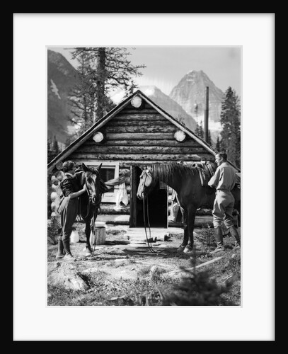 1920s 1930s couple in front of log cabin standing by horses with saddles both wearing jodhpurs assiniboine canada by Anonymous