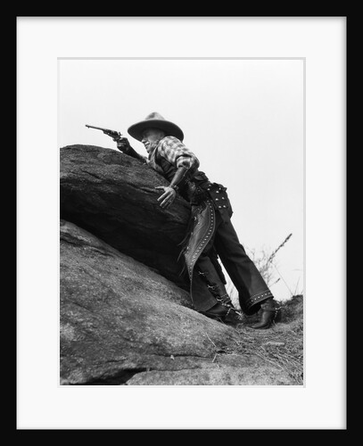 1920s cowboy among rocks aiming revolver by Anonymous