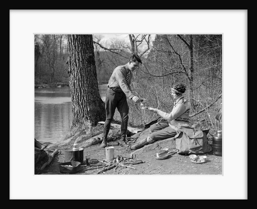 1920s 1930s man & woman camping by lake having picnic woman sitting man standing serving food to woman east creek swamp by Anonymous