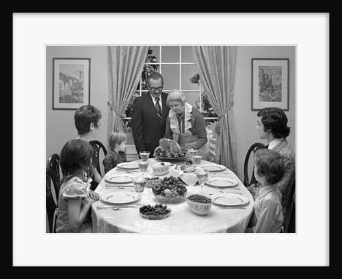 1970s three generation family sitting around dining room table with grandmother serving a baked ham by Anonymous
