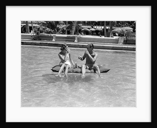 1930s 1940s couple drinking while floating in a pool on a rubber raft at florida resort by Anonymous
