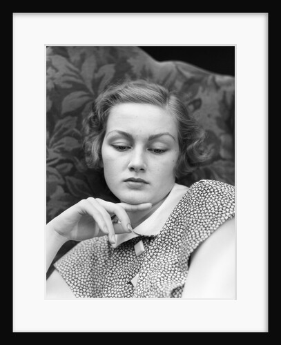 1930s portrait of woman looking down with sad expression and her chin resting on index finger by Anonymous