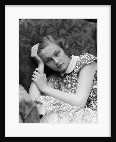1930s woman moping looking sad or depressed or with a headache leaning her head on her hand looking at camera by Anonymous