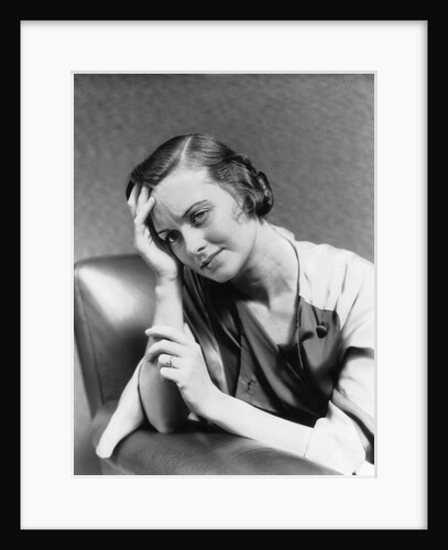 1930s 1940s woman sitting in chair worried sad expression one hand up to her forehead by Anonymous