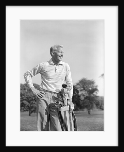 1960s smiling blond man standing with golf bag looking down fairway by Anonymous