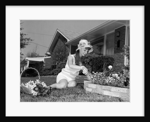 1960s young woman gardening in front lawn of brick house by Anonymous