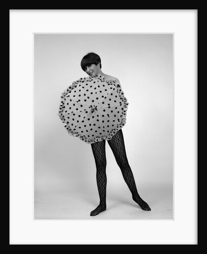 1960s full-length portrait of short- haired brunette in lacy hose covering naked torso with polka-dotted umbrella by Anonymous