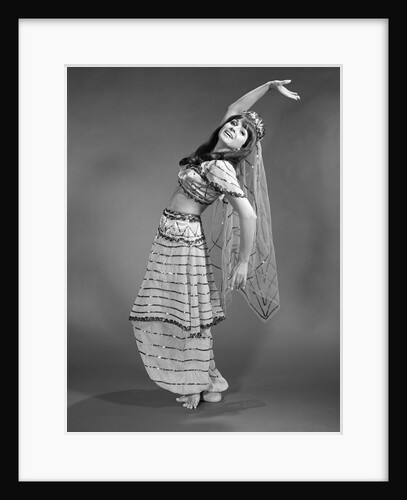 1960s woman in belly-dancer costume stretching back with arms out looking at camera by Anonymous