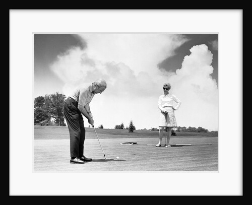 1960s older couple on golfing green man putting by Anonymous