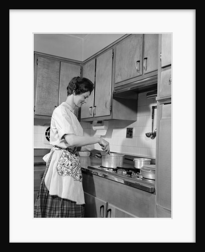 1960s woman kitchen cooking stirring pot on stove by Anonymous