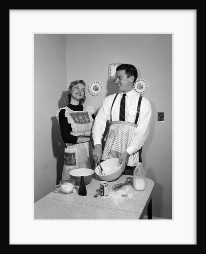 1950s satisfied amused smiling couple husband wife in kitchen cooking together by Anonymous