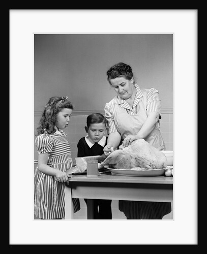 1940s mother son daughter in kitchen stuffing turkey for thanksgiving dinner by Anonymous
