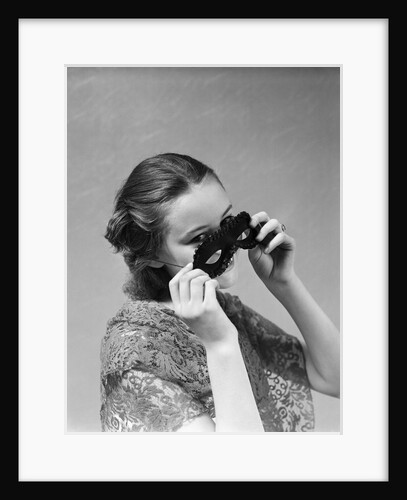 1930s 1940s woman putting on taking off black eye mask by Anonymous