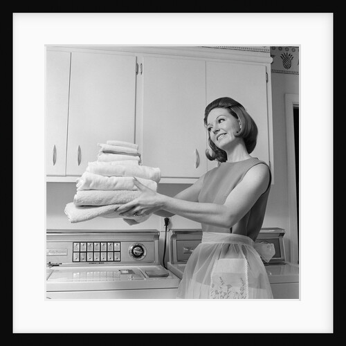 1960s satisfied woman homemaker holding folded laundry by Anonymous