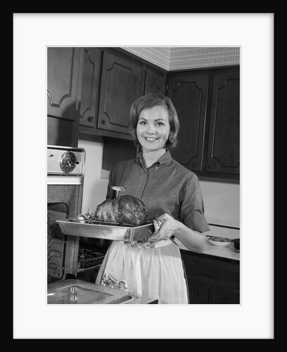 1960s smiling woman in kitchen taking roast out of oven looking at camera by Anonymous