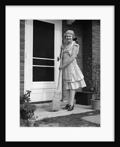 1940s smiling woman sweeping porch front door step with a broom looking at camera by Anonymous