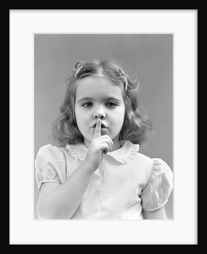 1940s 1950s girl with finger to lips making quiet shush gesture looking at camera by Anonymous