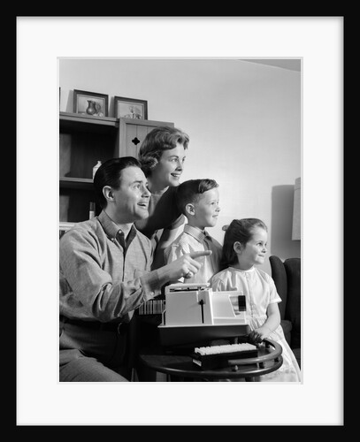 1960s happy family looking at slides on slide projector by Anonymous