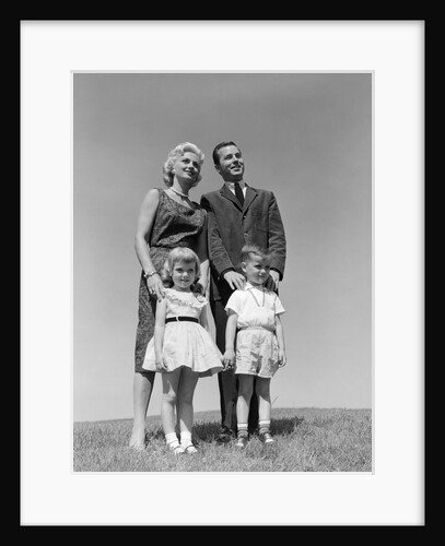 1950s 1960s portrait family standing in grass mother father daughter son by Anonymous