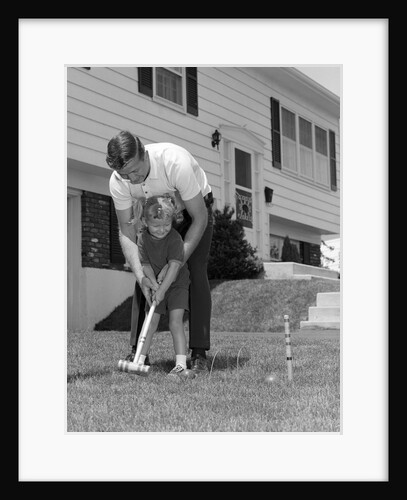 1960s father and young daughter playing croquet in yard by Anonymous