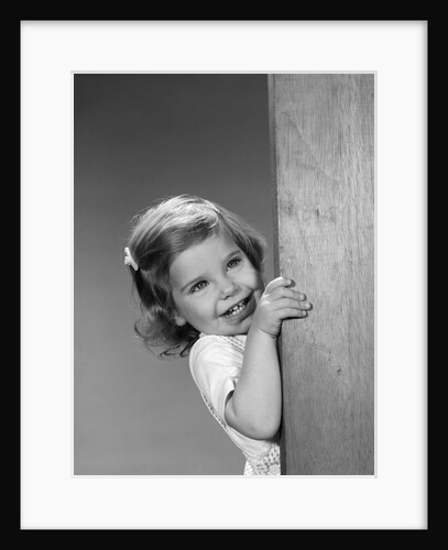 1960s child little girl smiling peeking around corner by Anonymous